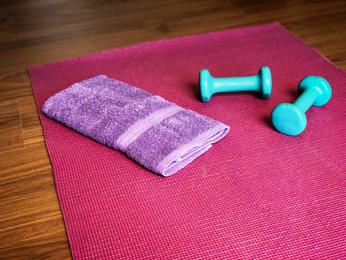 Woman applying sustainable yoga mat cleaning fitness solution with reusable cloth